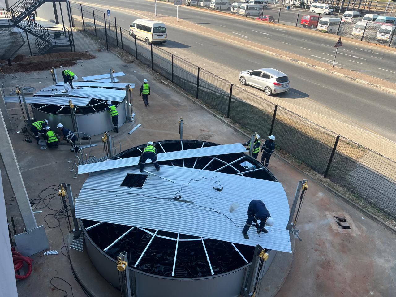 Videx installation team fitting roof sheeting on cylindrical water storage tanks at East Rand Mall